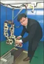  ?? LI WENFANG / CHINA DAILY ?? Huang Zhifeng adjusts his biped robot, which is able to take a big step while keeping its balance.