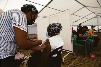  ?? Denis Farrell / Associated Press ?? A woman gets vaccinated in the Soweto township of Johannesbu­rg, South Africa. Doctors there report relatively mild symptoms so far among those infected with the new omicron variant.