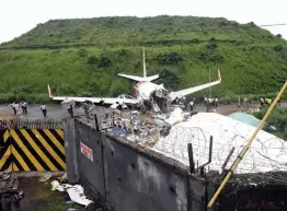  ?? — AP ?? Officials stand by the debris of the Air India Express flight that skidded off a runway while landing in Kozhikode, Kerala, on Saturday.