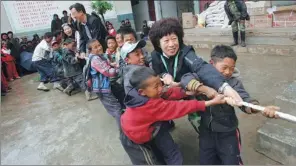  ??  ?? Zhang joins a tug-of-war at a primary school in Liangshan.