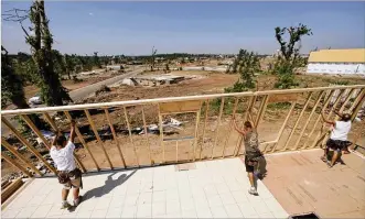  ?? CHARLIE RIEDEL / AP ?? Constructi­on workers raise a wall as they rebuild a tornado-damaged home in Joplin, Missouri, two months after a tornado destroyed a large swath of the community in 2011. Similar efforts are taking place across the Miami Valley after the devastatio­n of the Memorial Day tornadoes.