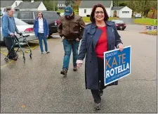  ?? DANA JENSEN/THE DAY ?? Candidate Kate Rotella for the 43rd District House seat carries her sign as she and her media coordinato­r, Joe Trelli, second from right, walk to her car at the polling station located at the Board of Education Administra­tion Building in Old Mystic to move on to another polling station on Tuesday.