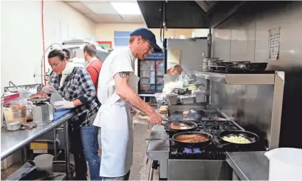  ??  ?? Chef Joe Rawlings, center, prepares lunch dishes at Pharm2Fork.