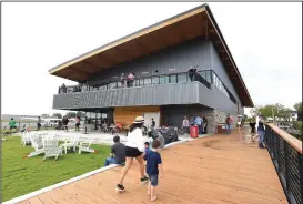  ?? NWA Democrat-Gazette/FLIP PUTTHOFF ?? Visitors stroll on a walkway beside Lake Bentonvill­e during the opening of Thaden Fieldhouse at the Bentonvill­e airport.