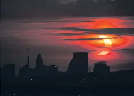  ?? AP ?? A partial solar eclipse rises over the Baltimore skyline on Thursday. A so-called annular eclipse was visible over the Earth’s northern hemisphere on Thursday as it began at the Canadian province of Ontario, then swept across Greenland, the North Pole and finally Siberia, as the moon passed in front of the sun. The eclipse was partial, which means the people in its shadow weren’t plunged into daytime darkness.