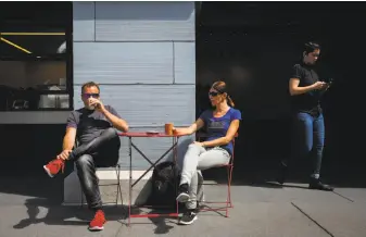  ?? Gabrielle Lurie / The Chronicle ?? Gottfried Elsenhaus (left) and Martina Elsenhaus, who are visiting from Switzerlan­d, sit outside the Blue Bottle Coffee stand at San Francisco’s Ferry Building.