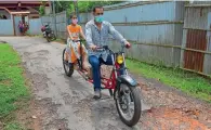  ??  ?? Partha Saha rides the modified bike with daughter Pragya Saha in front of his house in Aralia village, Tripura, on Thursday. —
ANI