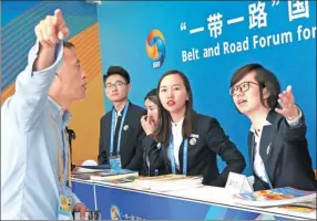  ?? ZOU HONG / CHINA DAILY ?? Volunteers help a journalist at the media center for the Belt and Road Forum for Internatio­nal Cooperatio­n. The media center opened on Friday in Beijing.