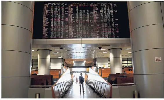  ?? — AP ?? Index down:People walking in front of private stock trading boards at a private stock market gallery in Kuala Lumpur. The FBM KLCI ended at 1,695.37 points, down 15.34 points, yesterday.