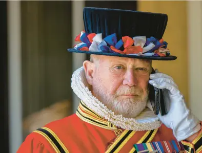  ?? BRANDON BELL/GETTY ?? A yeoman of the guard speaks on a cellphone in London. Phone etiquette has changed a lot since the device was invented in 1876 by Alexander Graham Bell.