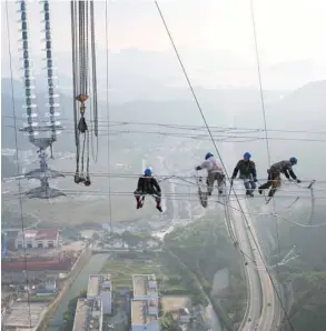  ?? — Reuters ?? province, China. Men work on cables connecting power transmissi­on towers in Zhoushan, Zhejiang