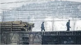  ??  ?? Soldiers walk the length of a freight train in a snowstorm in rural South Hamgyong province.