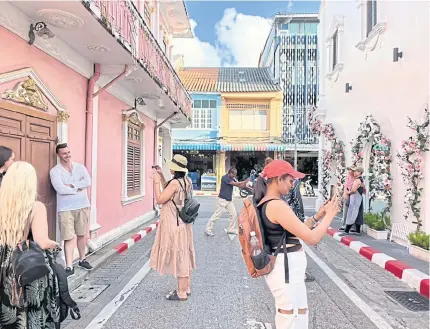  ?? ?? Tourists take photos in Old Phuket Town.