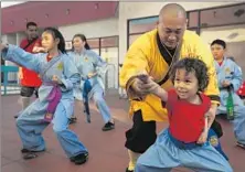  ??  ?? YANXU ADJUSTS the stance of Issei Sundius, 5. “The Shaolin philosophy is not about a name or a person,” Yanxu says. “It’s about what you have been able to learn.”