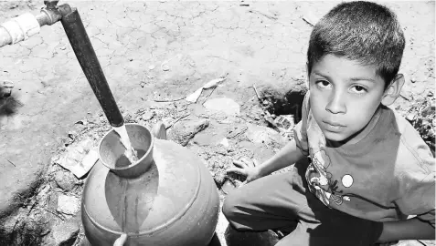  ??  ?? A child fills his jug with water at a community tap in Los Pinos, in the municipali­ty of Tacuba, in the western Salvadoran department of Ahuachapán. Access to piped water is still a problem in many rural communitie­s in Central America. — Edgardo Ayala...