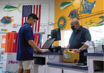  ?? DANIEL A. VARELA Miami Herald/ Daniel A. Varela ?? Pinch A Penny employee Julio Villamar, 19, checks out Alex Sanchez at the store at 11035 Bird Road. Supply chain issues have made it difficult to build, fix and maintain swimming pools and hot tubs, a Miami franchisee said.