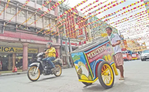  ?? SUNSTAR FOTO / MACKY LIM ?? An ice cream vendor peddles along San Pedro Street in Davao City as preparatio­ns shift to high gear for the Kadayawan sa Dabaw festivitie­s that will start tomorrow, Friday.