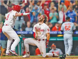  ?? AP PHOTO/MATT SLOCUM ?? The Philadelph­ia Phillies’ Bryce Harper (3) and Andrew Knapp (5) celebrate after Harper scored the winning run in the 10th inning against the visiting Baltimore Orioles on Sept. 21.