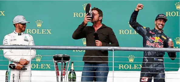  ?? Cheers: ?? Actor Gerard Butler (centre) drinks from a boot given to him by Daniel Ricciardo (right) while winner Lewis Hamilton looks on after the US Grand Prix at the Circuit of the Americas in Austin, Texas, on Sunday. — EPA