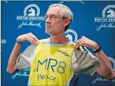  ?? ELISE AMENDOLA/AP PHOTO ?? 1968 Boston Marathon champion Amby Burfoot holds up a singlet during a news conference in Boston on April 17, 2014. Burfoot wore it when he ran the following week’s Boston Marathon for the Martin Richard foundation MR8. Martin Richard was one of the...