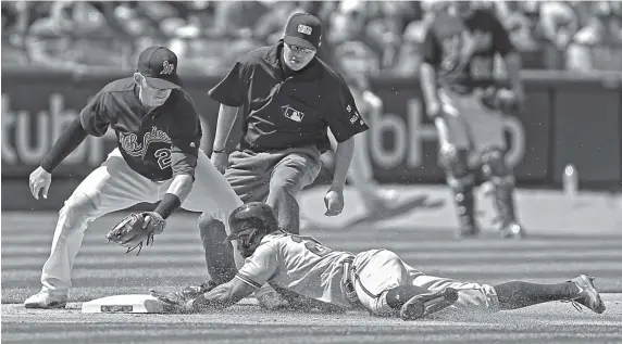  ?? PHOTOS BY THE ASSOCIATED PRESS ?? Above: The Atlanta Braves’ Danny Santana, right, slides in to steal third base ahead of the tag by the Oakland Athletics’ Ryon Healy in the seventh inning of Saturday’s game in Oakland, Calif. The Braves won 4-3 to clinch their fifth series win in the...