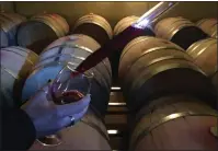  ?? JANET PODOLAK — THE NEWS-HERALD ?? Lauren Fiala uses a thief to draw a sample of wine directly from the barrel at South River Vineyard.