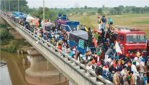  ??  ?? Farmers gather on a bridge as police block a road during a march to New Delhi to protest against the central government’s recent agricultur­al reforms, on the outskirts of Ambala yesterday.