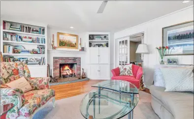  ??  ?? The living room with a fireplace, built-in shelves and cabinets, and a wall of glass overlooks the water.