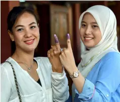  ??  ?? File photo shows young voters Zainatul Fadhli (right) and Intan Liana Azmi, showing their fingers marked in indelible ink during the recent GE14. — Bernama photo