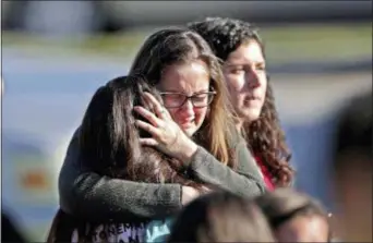  ?? JOHN MCCALL — SOUTH FLORIDA SUN-SENTINEL VIA AP ?? Students released from a lockdown embrace following a shooting at Marjory Stoneman Douglas High School in Parkland, Fla., Wednesday.