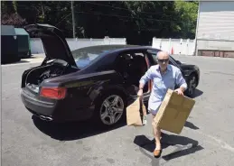  ?? H John Voorhees III / Hearst Connecticu­t Media ?? Paolo Martino, of New Milford, carries his recycling from his car at the New Milford Recycling Center in June.