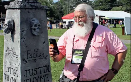  ?? / Doug Walker ?? Haunted Mysteries mega-event Gary Lindner, a geocacher from Lenoir City, Tennessee, takes a picture of the mythical Thyme family memorial obelisk, one of the decoration­s at the Haunted Mysteries Going Caching event in Rome Saturday.