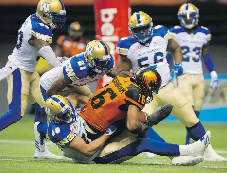  ?? GERRY KAHRMANN ?? B.C. Lions receiver Bryan Burnham is mobbed by the Winnipeg Blue Bombers’ defence on Friday night at B.C. Place Stadium.