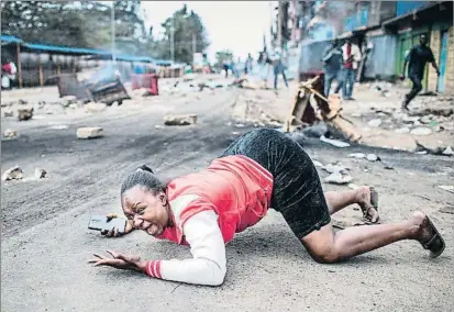  ?? LUIS TATO / AFP ?? Una mujer se arroja al suelo al paso de la policía en una protesta en el suburbio de Mathare, en Nairobi