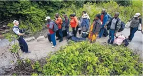  ?? THE ASSOCIATED PRESS ?? A Royal Canadian Mounted Police officer, left, standing in Saint-Bernard-de-Lacolle, Quebec, advises migrants that they are about to illegally cross from Champlain, N.Y., and will be arrested. Officials on both sides of the border first began to notice...