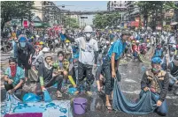  ?? HKUN LAT GETTY IMAGES ?? Anti-coup protesters hold drenched sheets in preparatio­n for the deployment of tear gas by riot police Monday in Yangon.