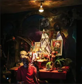  ?? ?? Juan Gonzalez sits next to his altar adorned with religious statues of Afro-cuban Santeria deities, including “Ochun” and a photo of the late Cuban leader Fidel Castro, at his home in El Cobre. Ochun, considered the goddess of female sensuality and motherhood, is associated with the Catholic Virgin of Charity of Cobre, Cuba’s patron saint.