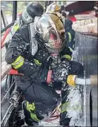  ??  ?? Un sapeur-pompier éteint un feu sur une péniche en bord de Seine à Paris.