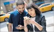  ?? Drew Angerer Getty Images ?? SAMEER UDDIN and Michelle Macias play the game outside a Nintendo store in New York. Police advise players to be aware of their surroundin­gs.