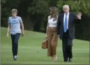  ?? CAROLYN KASTER — THE ASSOCIATED PRESS ?? President Donald Trump waves as he walks with first lady Melania Trump and their son, Barron Trump, from Marine One across the South Lawn to the White House in Washington, Sunday as they returned from Bedminster, N.J.