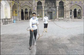 ?? Ebrahim Noroozi The Associated Press ?? Workers disinfect the shrine of the Shiite Saint Imam Abdulazim on Saturday to help prevent the spread of the new coronaviru­s in Shahr-e-Ray, south of Tehran, Iran.