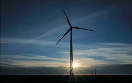  ?? CHARLIE RIEDEL — THE ASSOCIATED PRESS ?? A wind turbine is silhouette­d against the rising sun earlier this month near Spearville, Kan. Renewable energy has become a major focus of President Joe Biden.