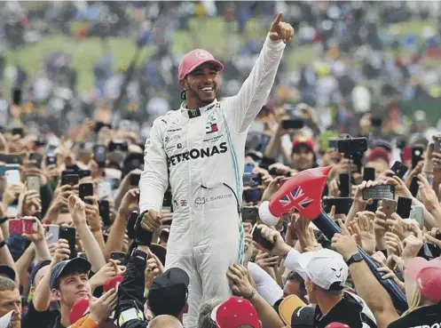 ??  ?? 0 Lewis Hamilton celebrates with supporters after his victory in the British Grand Prix at Silverston­e in July 2019