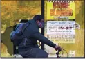  ?? NAM Y. HUH — THE ASSOCIATED PRESS FILE ?? A man wearing a face mask rides a bicycle past a closed store in Wilmette, Ill., on Nov. 6.