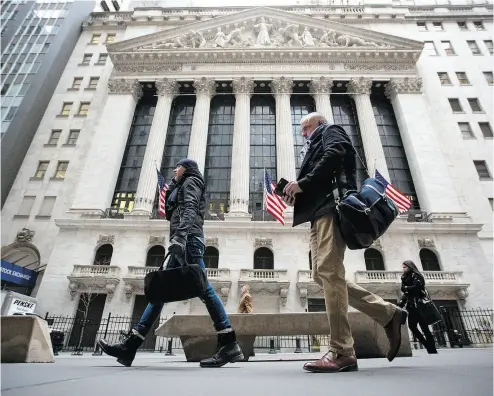  ?? MICHAEL NAGLE / BLOOMBERG ?? U. S. equity indexes climbed higher after a rocky start Tuesday, and the benchmark gauge for U. S. share volatility reversed course after hitting a two-year high. Above, pedestrian­s walk by the New York Stock Exchange in Manhattan.