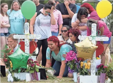  ??  ?? A girl becomes emotional as she kneels near a cross at a makeshift memorial outside Santa Fe High School on Monday in Santa Fe, Texas. Ten people were killed there Friday. COURTNEY SACCO/CALLER-TIMES