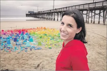  ?? Spencer Grant ?? JILL JOHNSON, who has spent the last year picking up plastic toys left behind by beachgoers, arranged some of them into a mandala by Newport Pier. She hopes the city will post signs reminding people to pick them up.