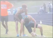  ?? STAFF PHOTO BY TED BLACK ?? Westlake High School senior Thomas Alcorn helps senior teammate Tobias Hurley up off the ground after the boys 1,600-meter relay on Wednesday afternoon at Huntingtow­n High School. Hurley ran the anchor leg for the Wolverines who won that event in 3...