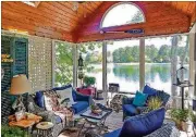  ??  ?? The vaulted sitting room with lake views was added onto the Roswell home. The upholstere­d navy and wicker furniture joins accessorie­s that show the homeowners’ love of the lake and birds.