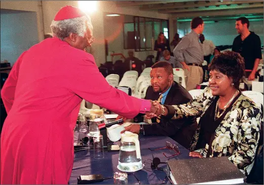  ?? (File Photo/Pool/AP/Odd Andersen) ?? Desmond Tutu (left), chair of the Truth and Reconcilia­tion Commission, shakes hands with Winnie Madikizela-Mandela (right) on the second day of commission hearings Nov. 25, 1997, in Johannesbu­rg. During the hearings, whose mission was to expose the abuses of apartheid, Tutu implored Madikizela-Mandela to apologize for her links to a gang that was implicated in murder, kidnapping and assault. Their anguished encounter still rankles some Black South Africans who think Tutu mistreated Madikizela-Mandela.